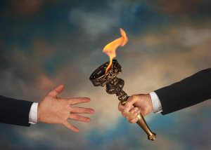 Businessman's outstretched arm passing a flaming torch to another businessman