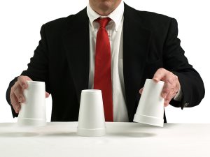 business man performing shell game scam with cups