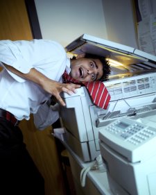 young businessman with head under copy machine