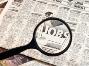Job searching newspaper with magnifying glass
