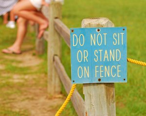 No siting on fence sign