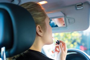 Woman puts on lipstick while driving