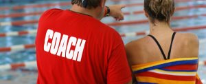 coach giving instruction to a young female swimmer