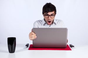 young man shocked with something he sees on his laptop