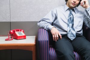 Midsection of businessman sitting by phone