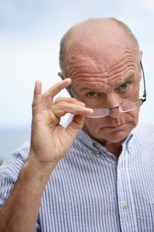 Senior skeptical man lowering eyeglasses