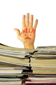 Hand with an inscription "Help!" over a pile of documents