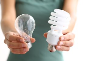 Hands holding traditional and energy efficient light bulbs