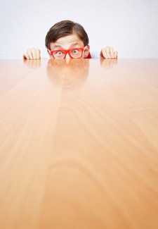 Scared nerd hiding behind a desk