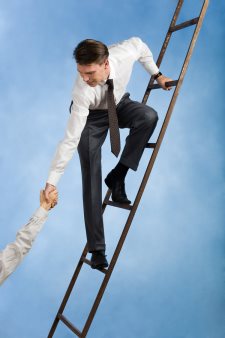businessman pulling someone up ladder