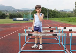 Child standing on a running track full of obstacles