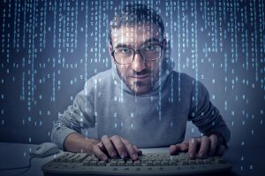 Young man typing on a keyboard in front of a computer screen