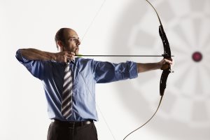 businessman aiming at target with bow and arrow