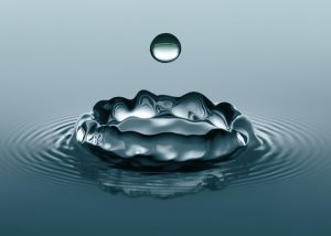 close-up of water droplets splashing into calm body of water