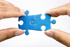Hands holding two jigsaw puzzle for joining.