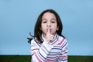 Girl giving the quiet sign with her finger and mouth