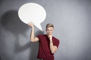 Questioning man holding white blank speech bubble