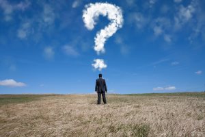 businessman standing alone at the field with a lot of questions in his mind