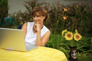 senior woman sitting in  garden  using a laptop computer