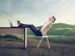 businessman relaxing at his desk in the middle of a green meadow