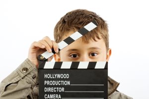 Boy with movie clapper board over white