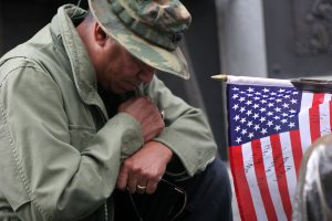 Veteran with head down by flag