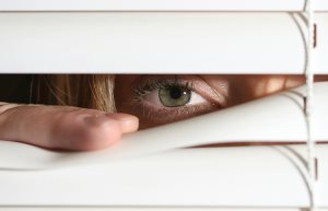 Woman Peering Through Blinds