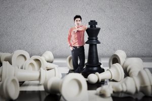 Businessman stand next to king chess game