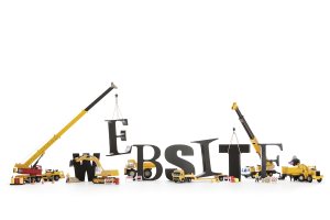 Black wooden alphabetic letters set showing "WEBSITE" being set up by group of construction machines 
