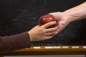 Student giving apple to teacher