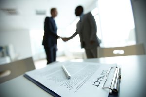 business contract on background of two employees handshaking