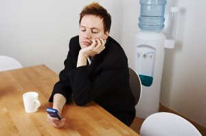 Bored businessman on cell phone by water cooler