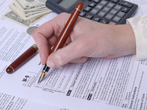 hand filling out W-9 income tax form