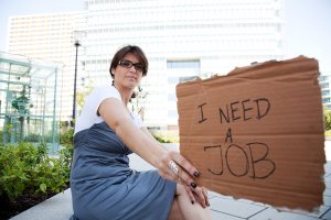 woman showing  cardboard message she needs a job