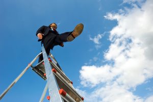 Business man standing on a ladder taking a blind leap