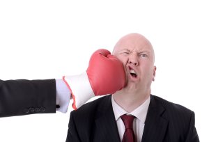 Businessman punched by red boxing glove