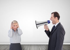 Businessman shouting with a megaphone at his scared colleague