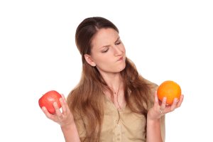 businesswoman making a difficult choice between an apple and orange