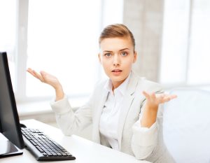 businesswoman shrugging in front of computer at work