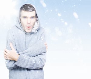 young man in hooded jumper freezing in the ice cold winter snow
