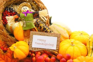 Happy Thanksgiving card and scarecrow among a cornucopia of autumn vegetables