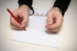 handcuffed man writing a confession 