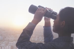 young businesswoman holding binoculars over cityscape of Beijing