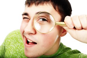 young man looking through the magnifying glass