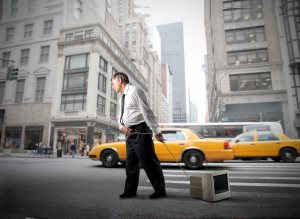 Businessman dragging a computer monitor on a city street