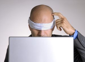Confused blindfolded bald head man using a computer
