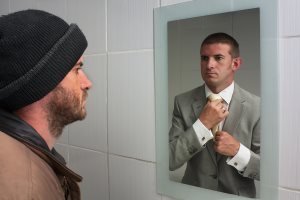 Unemployed man looking in mirror and seeing aspiration