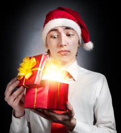 teen in Christmas hat opening red gift box with glowing light inside
