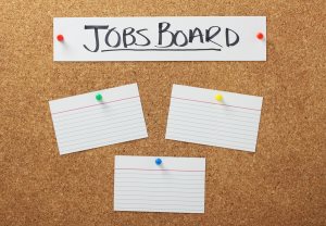 Jobs Board banner on a cork notice board with blank white note card