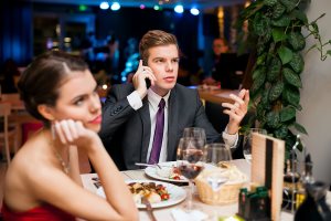 Man talking on a cell phone while on a date with his girlfriend
